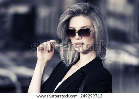 Young fashion business woman in sunglasses on a city street