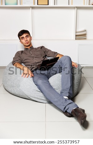 Young business man with tablet computer sitting on a chair
