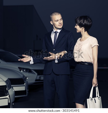 Young fashion business couple collecting new car at dealership lot