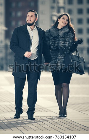Happy young fashion couple walking in city street. Stylish male and female models outdoor