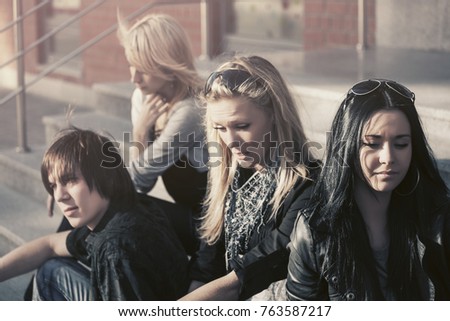 Young fashion men and women sitting on the steps. Stylish trendy male and female models outdoor