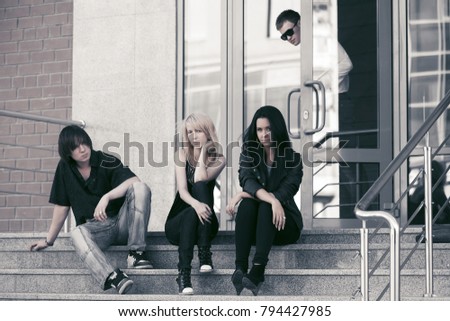 Young fashion men and women sitting on steps Stylish trendy male and female models outdoor