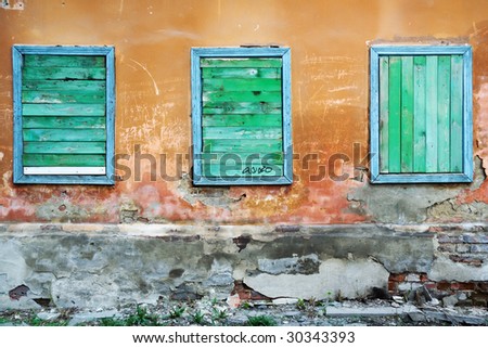 Three boarded up windows of an old rundown building.