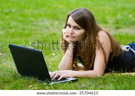 Young woman working on laptop in the field.