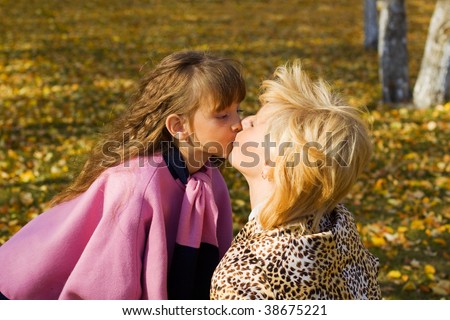 Mother and daughter kissing in the park.