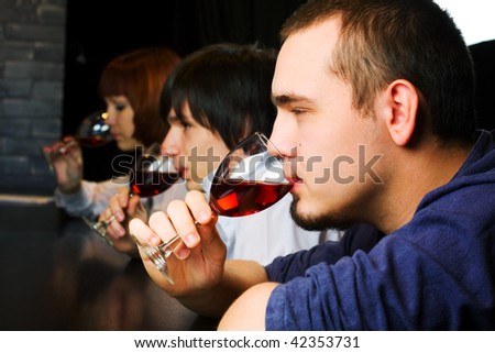 Young people drinking red wine on a bar counter.