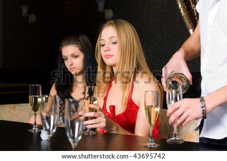 Two young women drinking champagne  in a bar.