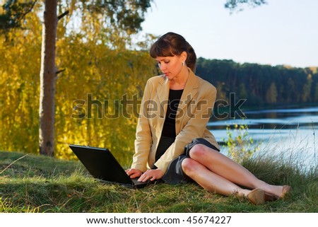 Young businesswoman using laptop on nature.