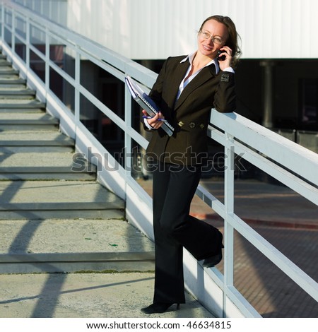 Happy businesswoman calls on phone at the stairway of airport terminal.