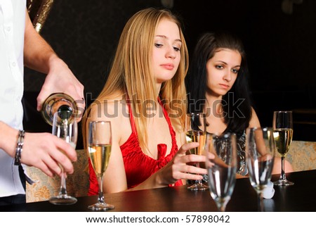 Two young women drinking champagne  in a bar.