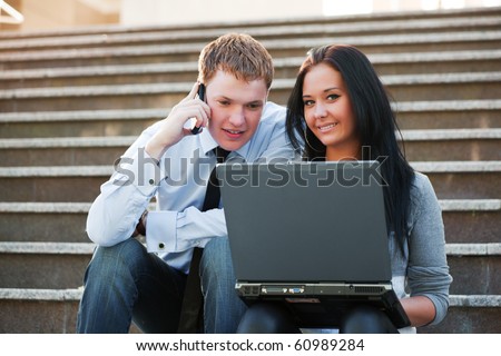 Young people with laptop on the steps.