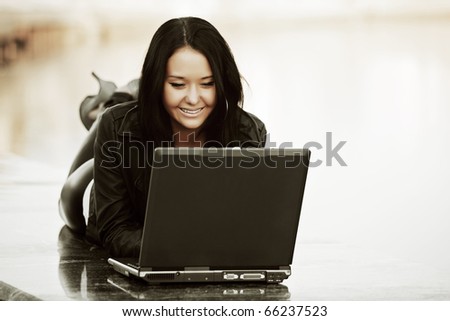Young woman with laptop against a river.