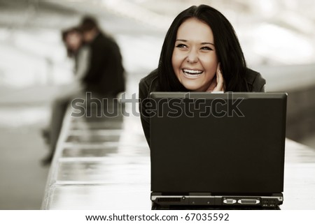 Young woman with laptop on the river embankment.