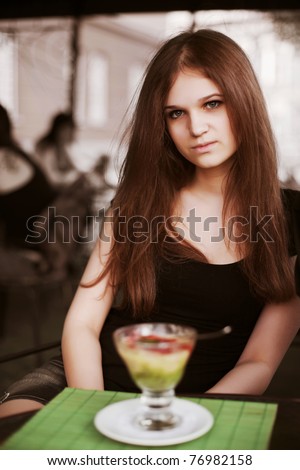 Young woman with ice cream at sidewalk cafe