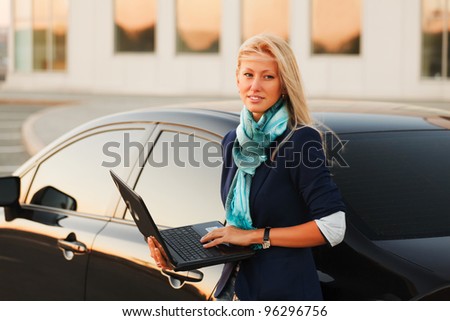 Young businesswoman using laptop against office windows