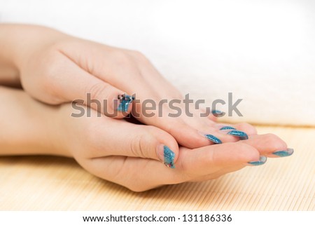 Manicure - Beautifully manicured woman hands in interesting pose, with blue nail design. Close up. Selective focus.