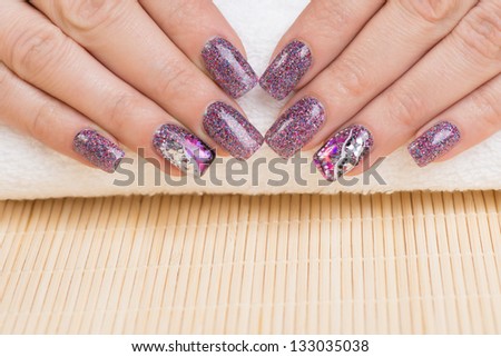 Manicure - Beauty treatment photo of nice manicured woman fingernails. Very interesting nail art with glitter purple, pink and silver nail polish