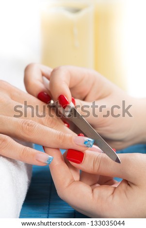 Manicure treatment - close up of female hands having manicure. Very interesting blue glitter nail art on nails.