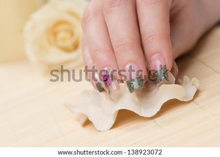 Manicure - Nice manicured woman fingernails touching seashell.