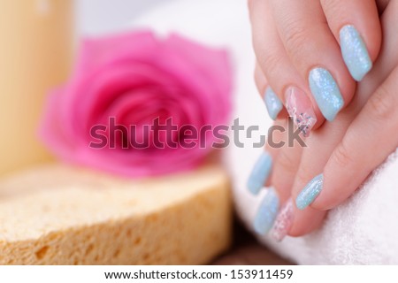 Manicure - Beautiful manicured woman\'s nails with blue nail polish and nail art on fourth fingers. Studio shot. Selective focus.