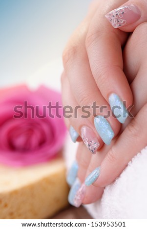 Manicure - Beautiful manicured woman\'s fingernails with glitter blue nail polish and nail art on some fingers. Studio shot. Selective focus.