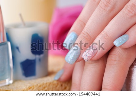 Manicure - Beautifully manicured woman\'s fingernails with glitter blue nail polish and nail art on fourth finger. Studio shot. Selective focus.
