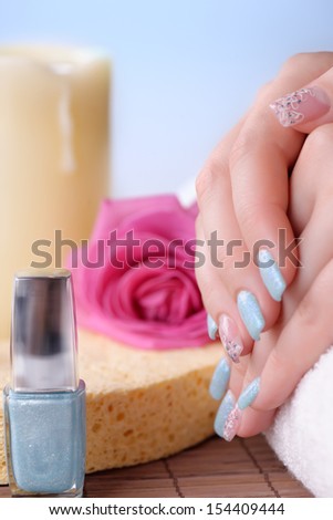 Manicure - Beautifully manicured woman\'s fingernails with glitter blue nail polish and nail art on fourth fingers. Studio shot. Selective focus.
