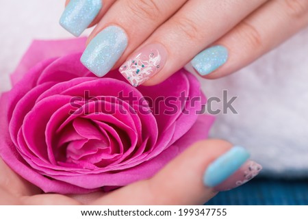 Manicure - Beautifully manicured woman\'s hand with interesting nail art touching flower. Close-up. Selective focus.