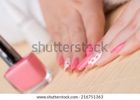 Manicure - Beauty treatment photo of nice manicured woman fingernails. Feminine nail art with nice pink and white nail polish. Selective focus on finger with white nail polish and pink dots.