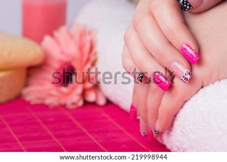 Manicure treatment. Close up of female hands holding nail file. Very interesting nail art on fingernails.