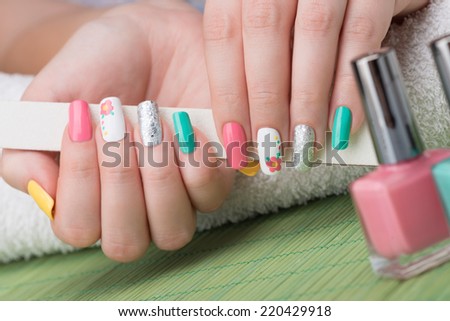 Manicure - Beauty treatment photo of nice feminine manicured woman fingernails holding nail file. Selective focus.