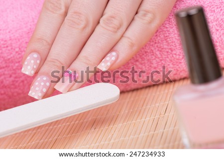 Manicure - Beauty treatment photo of nice manicured woman fingernails. Very nice feminine nail art with polka dots and bow detail. Selective focus.