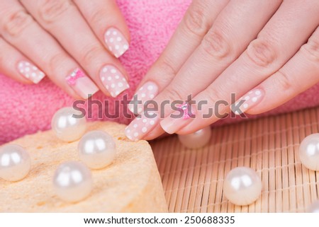 Manicure - Beauty treatment photo of nice manicured woman fingernails. Very nice feminine nail art with polka dots and bow detail. Selective focus on front finger with a bow,