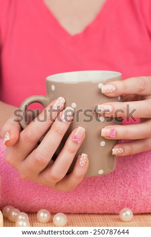 Manicure - Beauty treatment photo of nice manicured woman fingernails. Very nice feminine nail art with polka dots and bow detail. Selective focus.