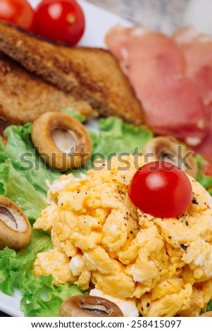 Scrambled eggs with white mushrooms and cherry tomatoes. Selective focus on scrambled eggs and cherry tomato.