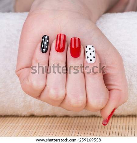 Manicure - Beauty treatment photo of nice manicured woman fingernails. Very nice feminine nail art with nice red, white and black nail polish.