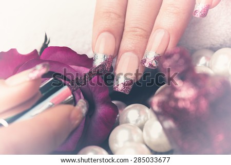 Manicure - Beauty treatment photo of nice manicured woman fingernails. Very nice feminine nail art with silver and purple glitter nail polish. Processed in retro, vintage colors. Selective focus