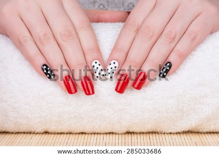 Manicure - Beauty treatment photo of nice manicured woman fingernails. Very nice feminine nail art with nice red, white and black nail polish.