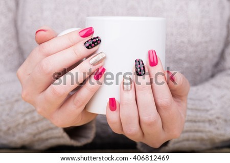 Manicure - Beauty treatment photo of nice manicured woman fingernails holding a cup. Very nice feminine nail art with nice pink,black and gold nail polish. Processed in retro colors. Selective focus.