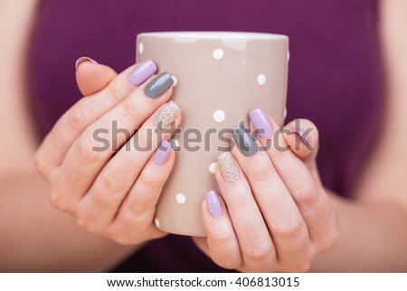 Manicure - Beauty photo of nice manicured woman fingernails holding a cup. Very nice feminine nail art with nice purple,silver and grayish nail polish. Processed in retro colors. Selective focus.