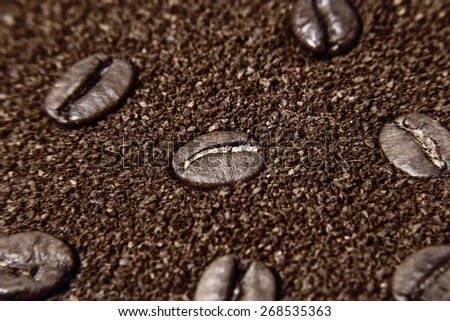 Macro of grains coffee over ground coffee background