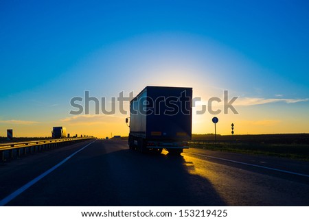 Silhouette of a truck on road at sunset