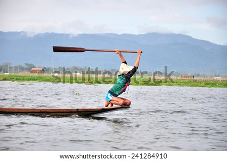 INLE LAKET, MYANMAR - CIRCA NOVEMBER 2014:Fisherman in wooden boat using a coop-like trap with net to catch fish in Inle lake, Myanmar