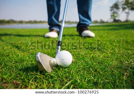 Close up of golf ball on green grass with the driver positioned ready to hit the ball