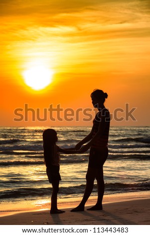Silhouette mother with daughter ashore on sunset