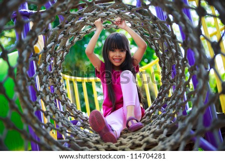 Asian Little Girl Enjoys Playing In A Children Playground, Outdoor Portrait