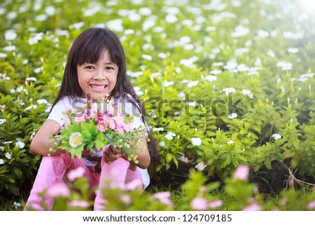 Asian little girl with flower in field of flowers
