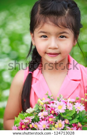 Closeup asian little girl with flower in field of flowers