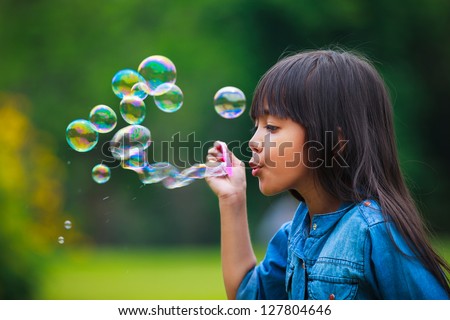 Asian Little Girl Is Blowing A Soap Bubbles, Outdoor Portrait