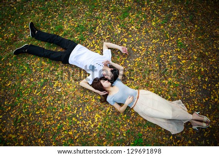 Asian couple laying down outdoor in park looking happy on fall ground Asian couple laying down outdoor in park looking happy on fall ground
